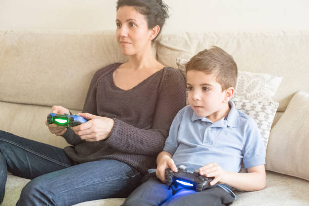 Mother and son playing on console with Videogames joystick in the living room